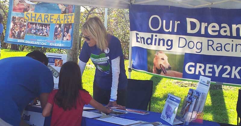 Board member Kathy Pelton speaks with visitors about dog racing